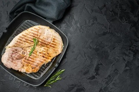 Grilled bone in pork shoulder in grill pan with rosemary on dark textured b.. Stockfoto's