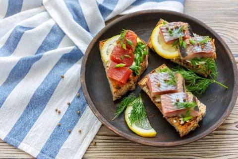 Grilled bread with chunks of herring, caviar and chives. Stock Photos