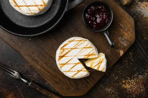 Grilled camembert or brie cheese on old dark rustic table background, top view Stock Photos