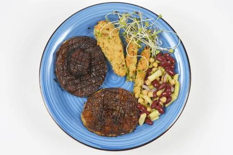 Grilled celeriac steaks and breaded celery stalks on a plate Stock Photos