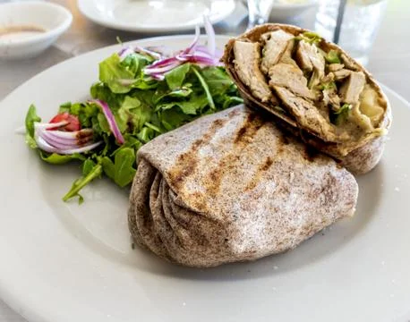 A grilled Chicken Caesar wrap rests on a rustic caf table. Stock Photos