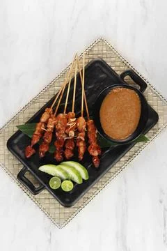 Grilled chicken satay with peanut butter sauce garnish with cucumber and or.. Stock Photos