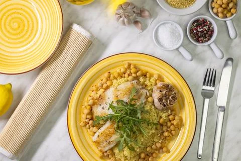 Grilled cod with couscous, chicken pea and baked garlic Stock Photos
