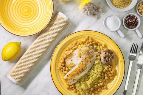Grilled cod with couscous, chicken pea and baked garlic Stock Photos