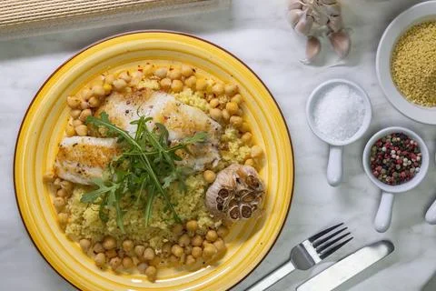 Grilled cod with couscous, chicken pea and baked garlic Stock Photos
