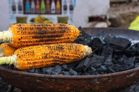 Grilled corn on the cob roasted over charcoal Stock Photos