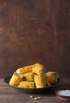 Grilled corn cobs on the brown rustic background. Side view with copy space o Foto stock