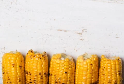 Grilled corn cobs on the rustic background. Top view with horizontal copy spa Stock Photos