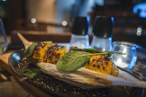 Grilled Corn on Dark Platter with Sage in Tarifa Restaurant Setting Stock Photos