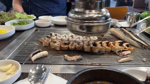Grilled Eel Sizzling on Tabletop Grill Beneath Restaurant Exhaust Hood Video stock 342343742