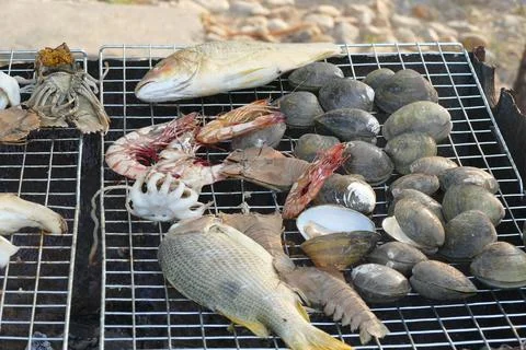 Grilled fish and shellfish on charcoal grill in Thailand. Stock Photos