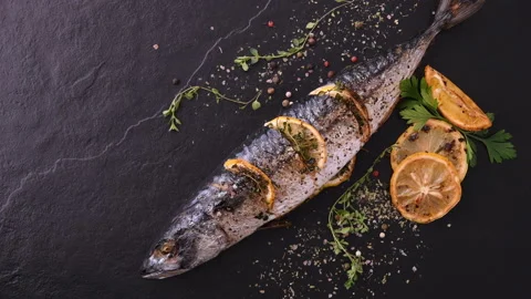 Grilled fish and various vegetables on black stone background Stock Footage 145189244