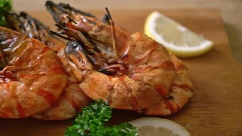 Grilled fish with lemon slice and herbs on wooden table Stock Photos