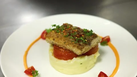 Grilled fish with mashed potato and veggies on top served on a white plate Stock Footage 302906198