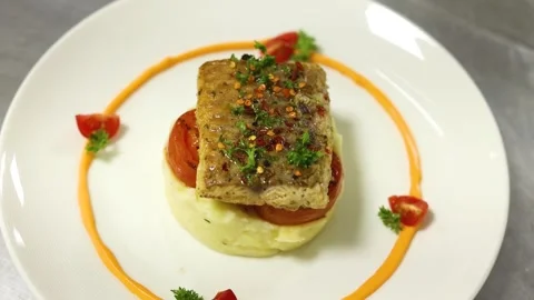 Grilled fish with mashed potato and veggies on top served on a white plate Stock Footage 302906202