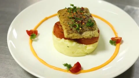 Grilled fish with mashed potato and veggies on top served on a white plate Stock Footage 302906211