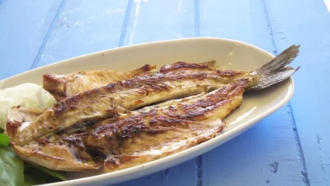 Grilled fish with onion and rocket leaves on the plate close up pan shot. Vídeos de archivo 80314285