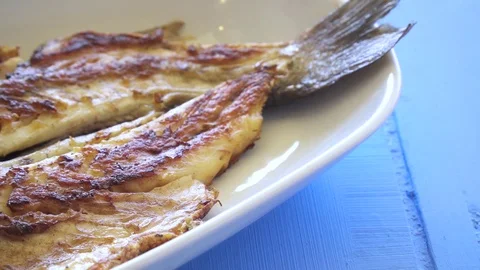 Grilled fish with onion and rocket leaves on the plate close up pan shot. Stock Footage 80314652