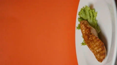 Grilled fish in a rotating plate on an orange background. Ready meals Stock Footage 163906072