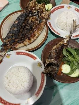 Grilled fish served with rice, vegetable and sambal on banana leaf. Stock Photos