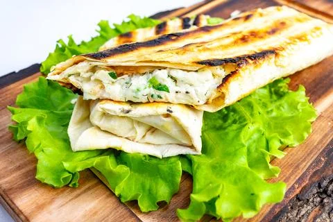Grilled flatbread wrap filled with savory ingredients on fresh greens Stock Photos