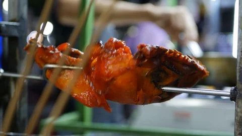 Grilled half of chicken on automatic spit, night asian market. 4k Stock Footage 104141379