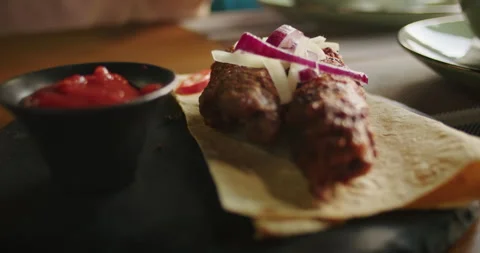 Grilled kebabs on flatbread with fresh onions and side of ketchup. Gourmet food Stock Footage 265014089