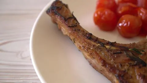 Grilled lamb chop with cherry tomatoes on a white plate Stock Photos