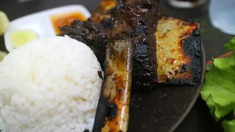 Grilled lamb chops with rice and salad on a black plate Stock Photos