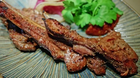 Grilled lamb chops served with pickled onions and fresh parsley on ceramic .. Stock Footage 339755133