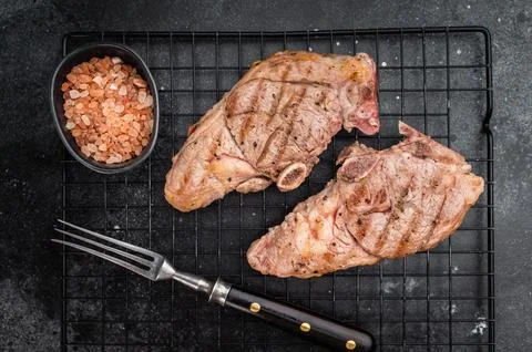 Grilled lamb chump chops on cooling rack over dark background, roasted sirl.. Stock Photos