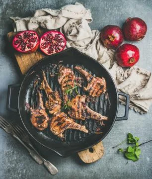 Grilled lamb meat chops served with fresh pomegranates, grey background Stock Photos
