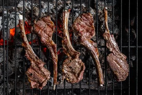 Grilled lamb mutton chop steaks on barbecue, outdoor BBQ grill with fire. Top Stock Photos