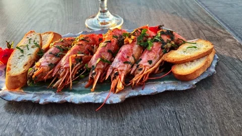 Grilled langoustines served on a platter with toasted bread and herbs in an Video stock 337501168