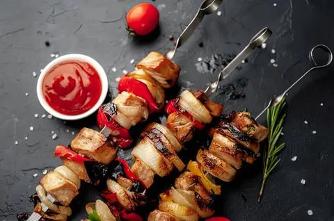 Grilled meat and vegetable skewers with ketchup on dark background Stock Photos
