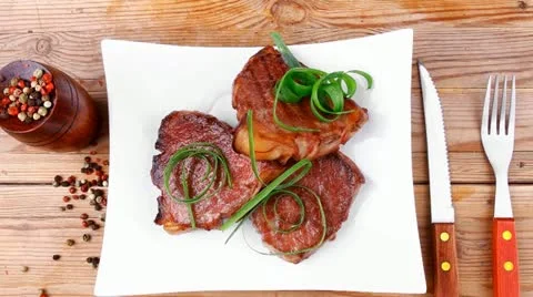 Grilled meat beef steaks strips on white plate with pepper and cutlery Vídeos de archivo 21362552
