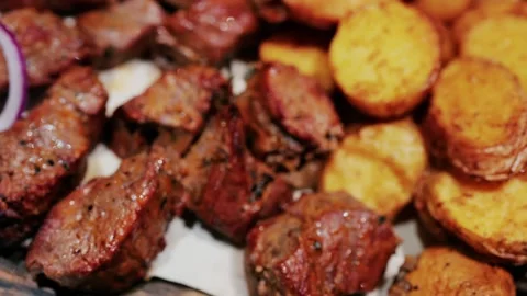 Grilled meat chunks with roasted potatoes and red onions served on wooden b.. Stock Footage 339118048