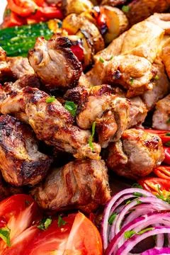 Grilled meat platter featuring assorted cuts and fresh vegetables Stock Photos