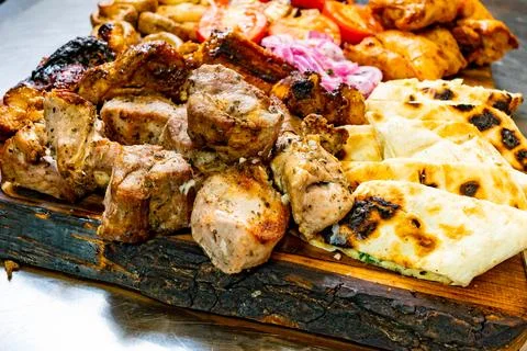 Grilled meat platter with flatbreads and vegetables served on wooden board Stock Photos