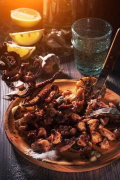 Grilled octopus tentacles on skewer on rustic plate. Stock Photos