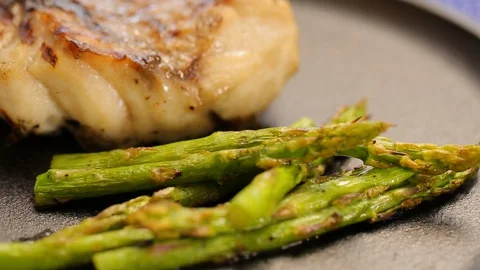 Grilled or fried fish with roasted asparagus A Video stock 120400269