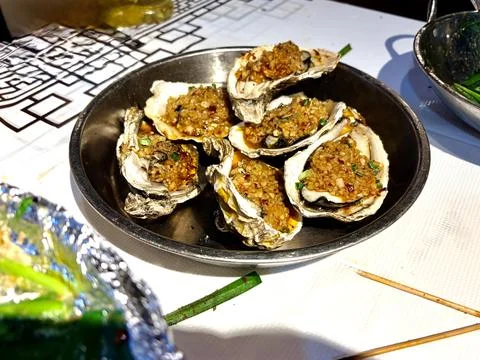 Grilled Oysters with Garlic and Herbs in a Metal Bowl. Fotos de archivo