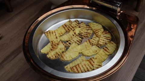 Grilled pineapple slices in copper chafing dish at buffet 库存影片 333811059
