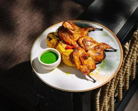 Grilled quail with roasted corn, green sauce Stock Photos