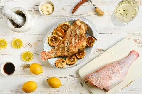 Grilled red snapper served on a dish with lemons and sauce on a wooden table Foto stock