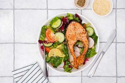 Grilled salmon and fresh vegetables: tomatoes, cucumber, lemon, radish on bricks Stock Photos