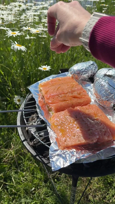 Grilled salmon being salted by hand, sizzling and flavorful Stock Footage 310116778