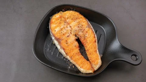 Grilled salmon with cherry tomatoes, thyme and lemon on a small black grill pan. Stock Footage 177438548