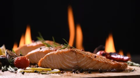 Grilled salmon fish with various vegetables on pan on the flaming grill Видео 129923636