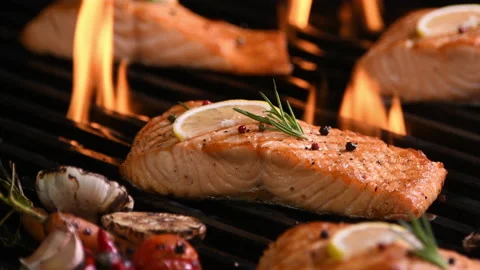 Grilled salmon fish with various vegetables on the flaming grill Vidéo 145187738
